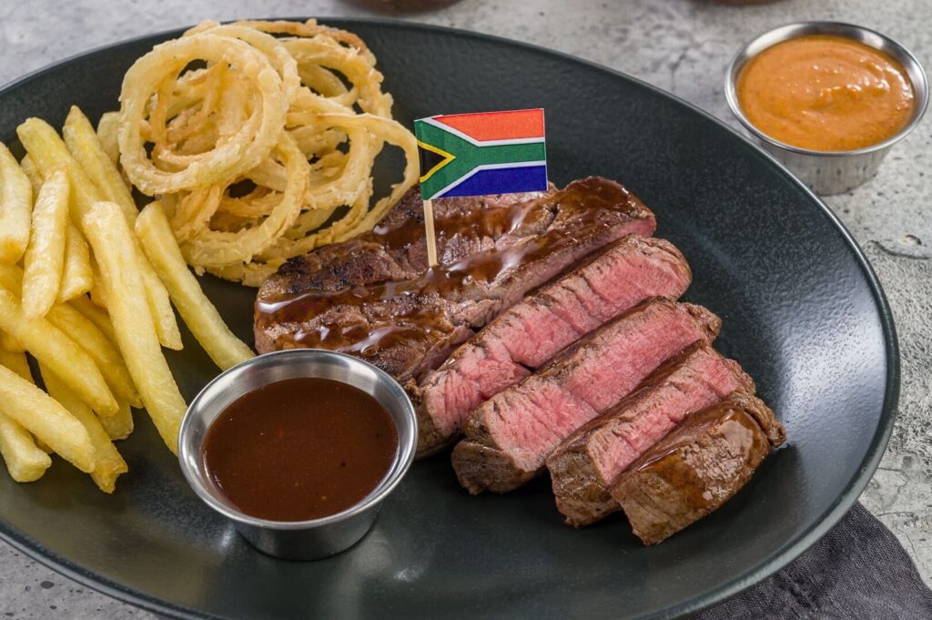Hyperama steak plate with sliced beef, fries, onion rings, and sauces.