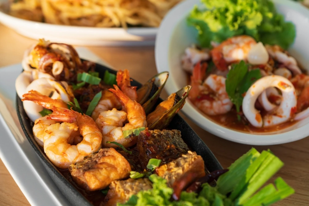 Casual dining seafood platter with grilled prawns, calamari, mussels, and fresh herbs served in a relaxed restaurant setting.