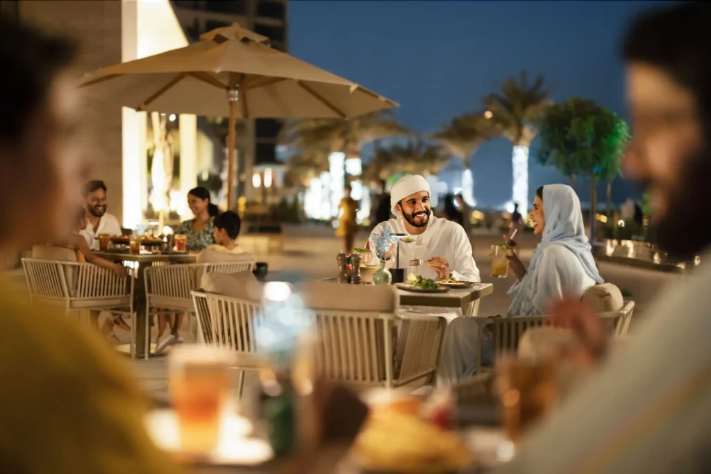 Diners enjoying an evening meal at an outdoor restaurant terrace in Abu Dhabi, capturing the city's vibrant al fresco dining scene.