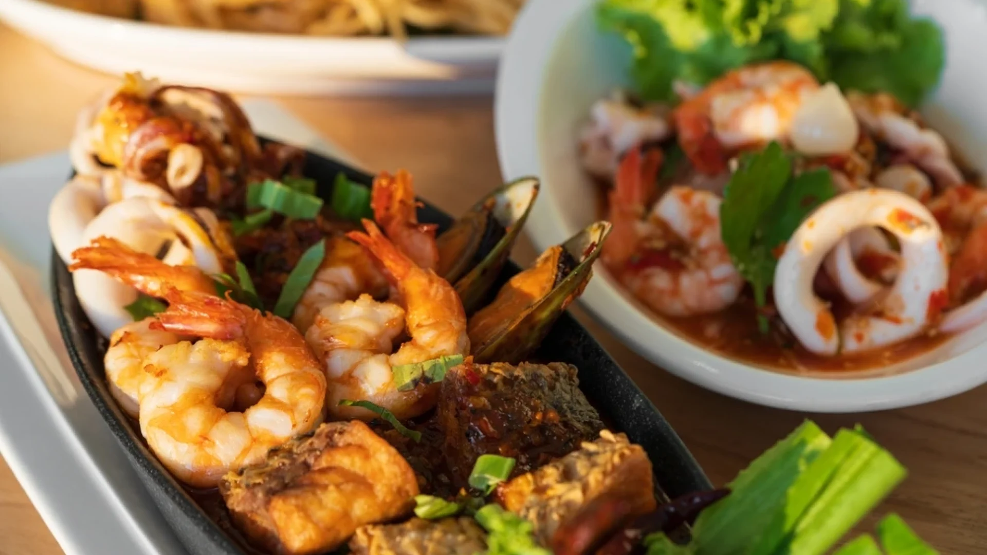 Casual dining seafood platter with grilled prawns, calamari, mussels, and fresh herbs served in a relaxed restaurant setting.