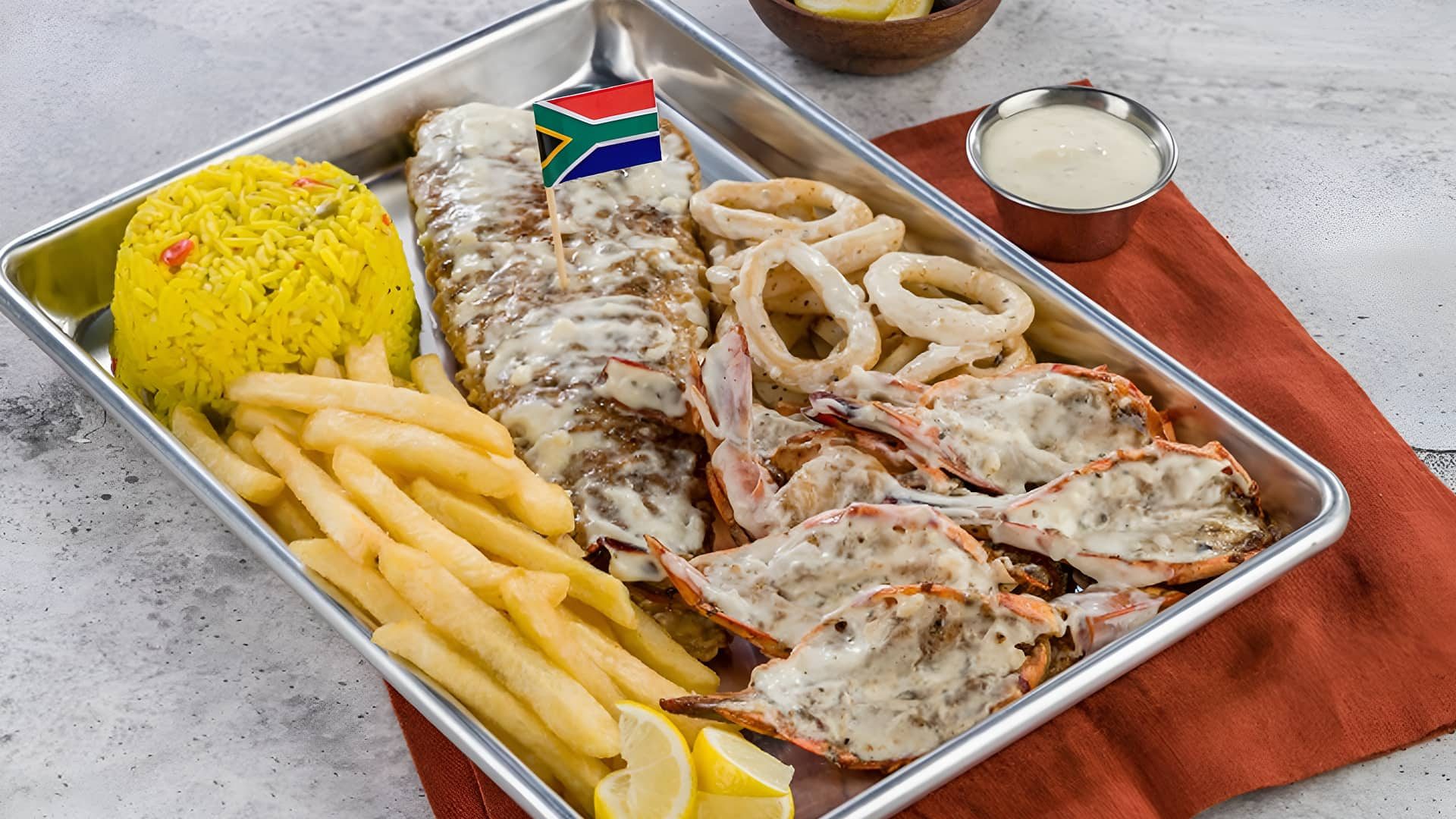 Seafood platter with grilled fish, calamari, prawns, fries, and rice served